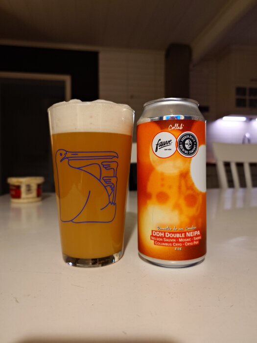 Ölglas med skummande orangefärgad öl bredvid en burk med etikett "DDH Double NEIPA" på ett bord i ett kök.