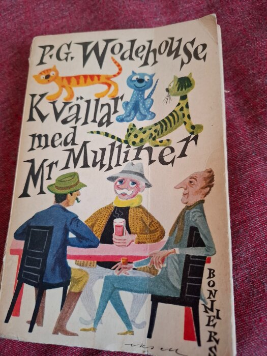 En bok med titeln "Kvällar med Mr Mulliner" av P.G. Wodehouse, med tecknade figurer och katter på omslaget.
