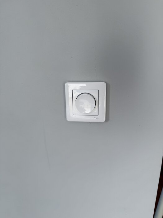 En hvid vægkontakt monteret på en grå væg. Den er planlagt at blive tilsluttet en ny lyskontakt til en loftlampe.
