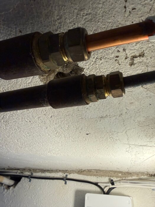 Koppar- och stålrör i ett källartak med kopplingar, del av ett värmesystem, planeras för omläggning och tillägg av fler element.