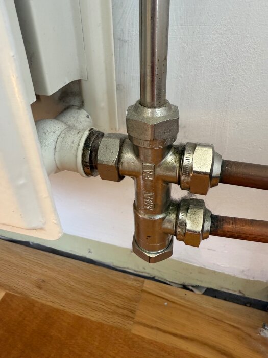 Värmeelementanslutning med rör och ventil i närbild, visar kopplingen mellan elementet och kopparrör i ett hem med två rörs system.