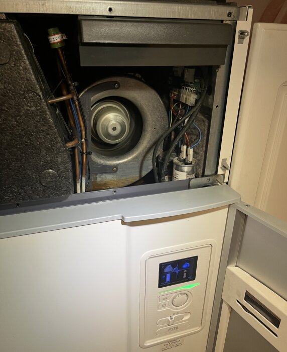 Elektroniken i en öppnad Nibe F730 värmepump syns med fläkt och kretskort, där användaren försöker felsöka problem med vattenläckage.