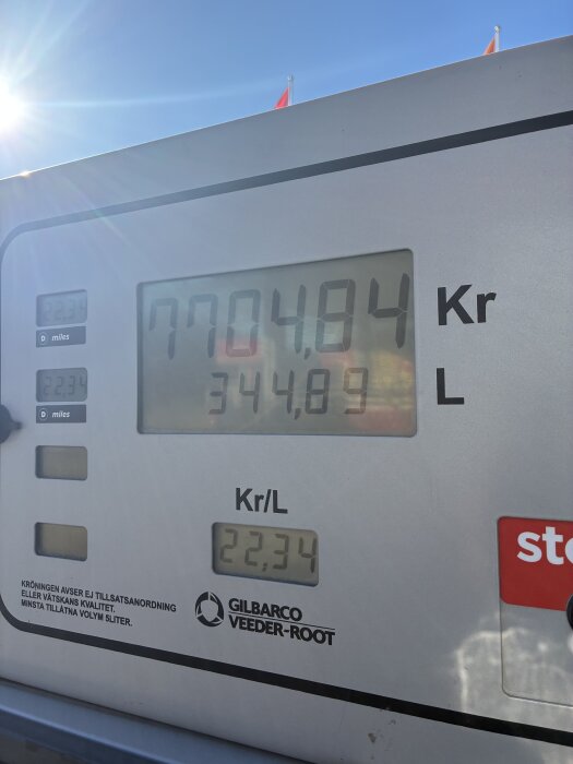 Tankstationens display visar att 344,89 liter kostar 7704,84 kr med ett pris på 22,34 kr/l. Solen skiner i bakgrunden.