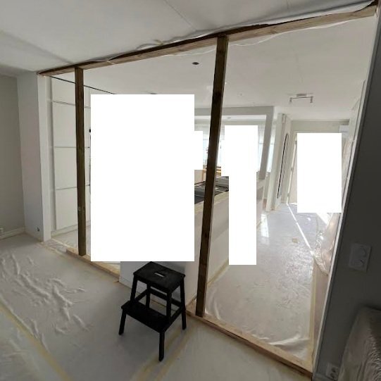 Renovering av ett rum med skyddsplast på golvet, trästomme för vägg och en stege.