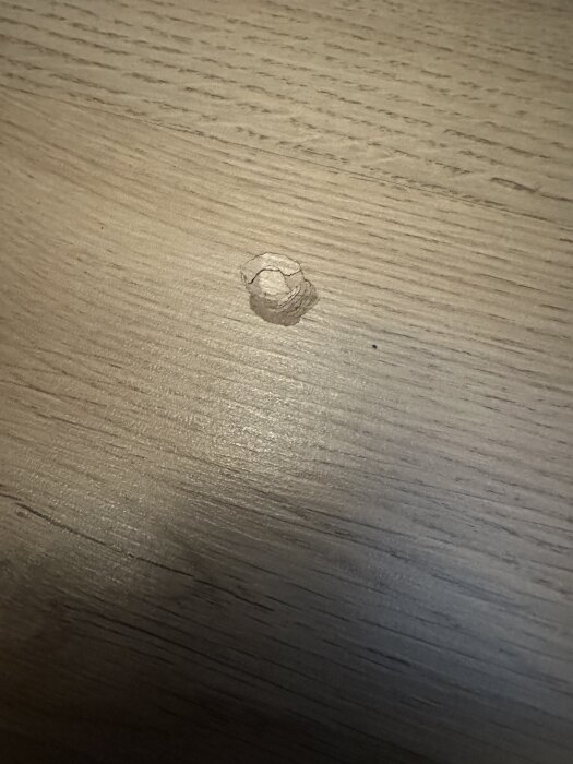 Hål eller jack i ett ljust laminatgolv, sett uppifrån.