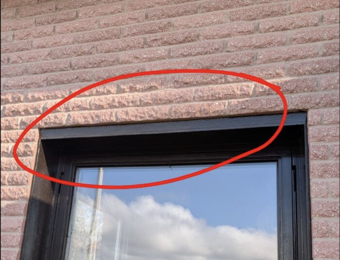 Tegelvägg med fönster där överliggande tegel är markerat med en röd cirkel.