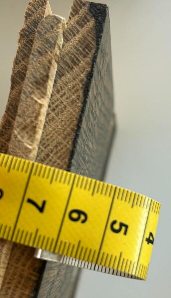 Närbild på kanten av ett parkettgolv med mörk bets, mätdon visar tjocklek på 8 mm från not/spont till ytan.