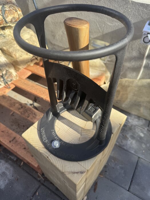 En vedkluvenhet på ett träblock, med ett handtag och svart metallram, utomhus.