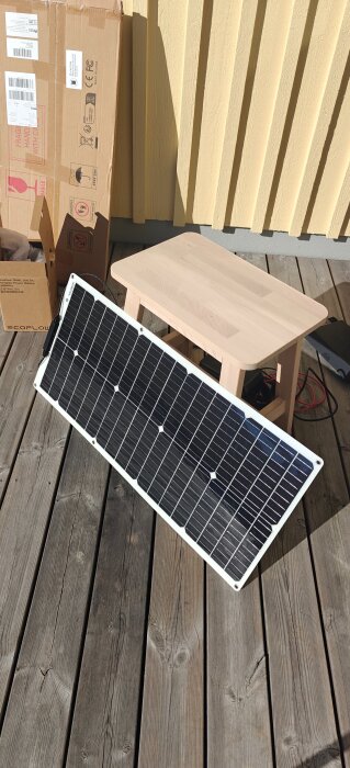 Solpanel på altan mot trävägg, prövad i solsken.