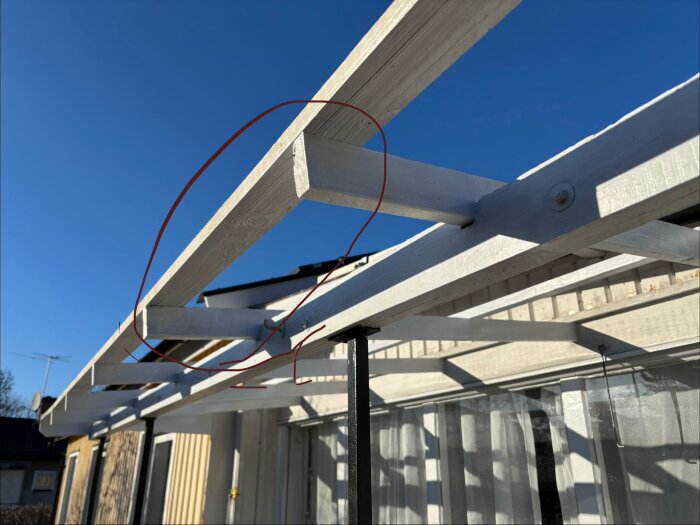 Träramverk till veranda under uppbyggnad med markering för spottar, ska täckas med plasttak, blå himmel i bakgrunden.