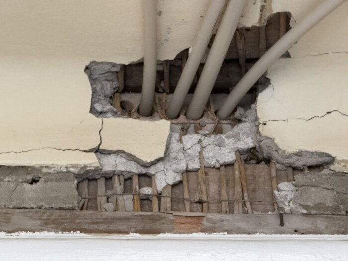 Tak med gipsplatta, elrör och synliga skador samt sprickor i ett äldre hus från 1916, visar utmaningar vid renovering.