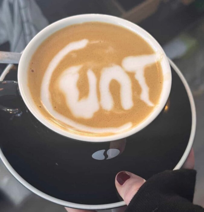 En kopp latte där mjölkskummet har bildat ord istället för ett palmmotiv.