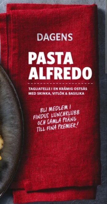 Förpackning av Findus Pasta Alfredo, tagliatelle i ostsås med skinka, vitlök och basilika, på en röd servett.