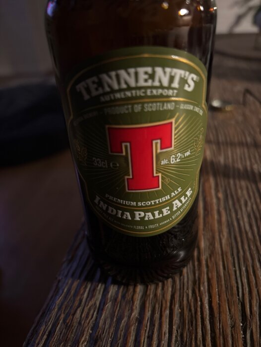 Flaska Tennent's India Pale Ale på ett träbord.