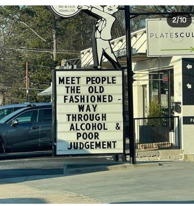 Skylt utanför en bar med texten: "Meet people the old fashioned way through alcohol & poor judgement" i en urban miljö.