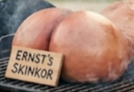 Rökt skinka på grill med en skylt som lyder "Ernst’s skinkor".