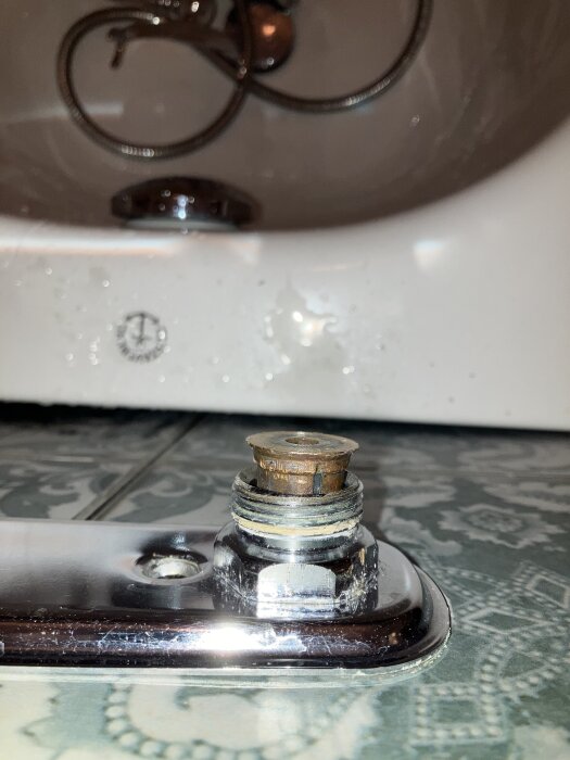 Närbild av ett badkarsblandarfäste med synliga tecken på läckage och en sliten packning som verkar ha rostat.