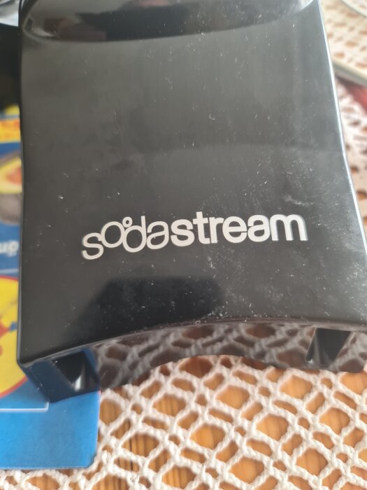 Närbild på en kolsyremaskin av märket SodaStream, placerad på ett bord med nätduk.