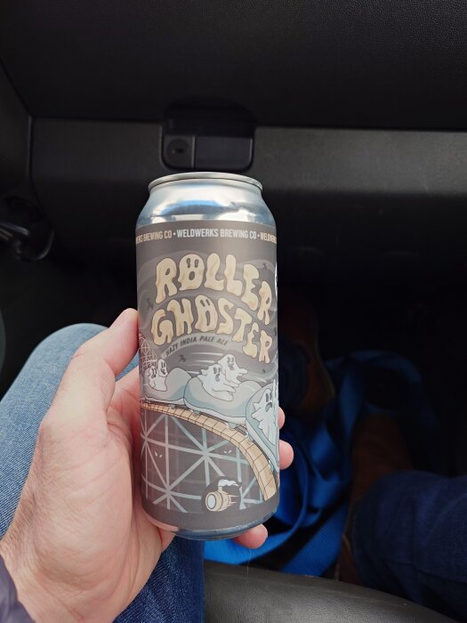 En hand håller en ölburk med texten "Roller Ghoster" och illustrationer av spöken på en berg-och-dalbana.
