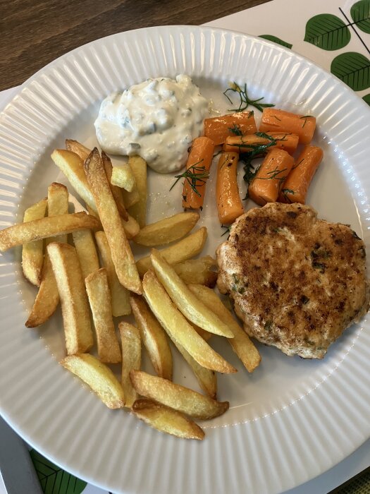 Stekt potatis, en kycklingfärsbiff, gräddfilsbaserad sås och ugnsrostade morötter med dill på en vit tallrik.