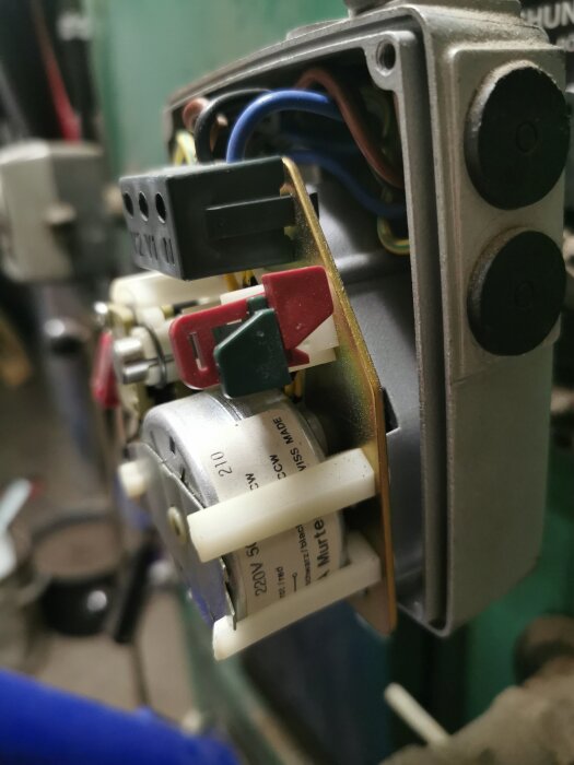 Närbild på en elektrisk komponent med flera färgade kablar och etikett som visar "220V".