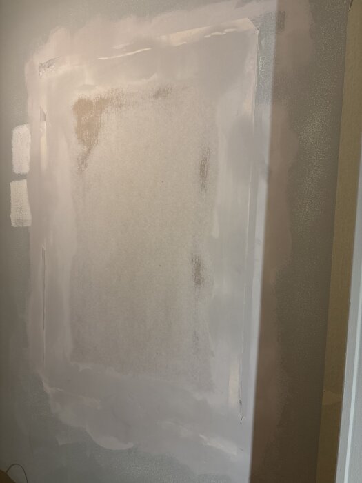 Vägg med spacklad yta och synliga kanter från pappremsor, delvis nedslipad, i ett hemrenoveringsprojekt.