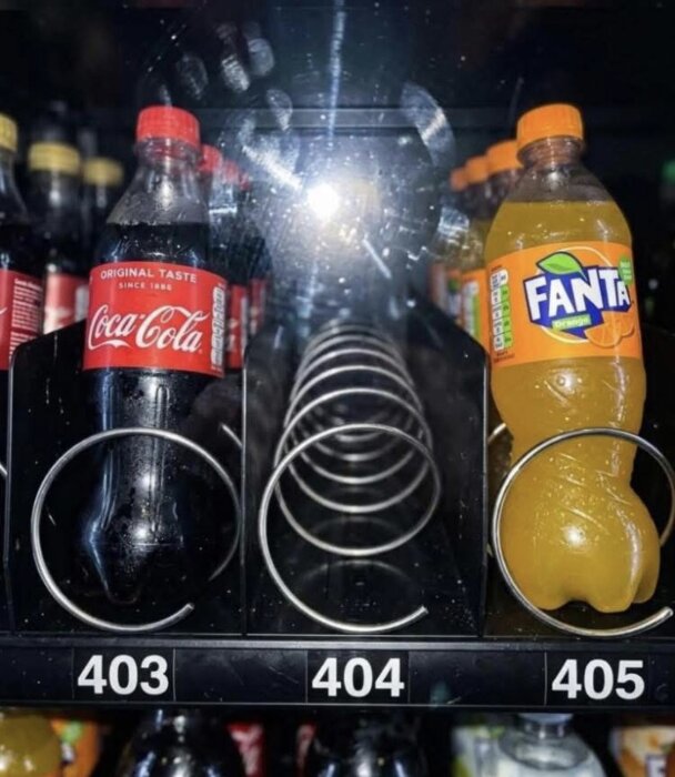 Läskautomaten har tom plats i mitten med två drycker: Coca-Cola på vänster sida, Fanta på höger sida. Numrering under varje plats: 403, 404, 405.