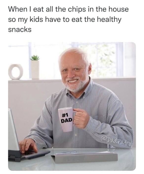 Äldre man vid dator håller en kopp med texten "#1 DAD", ler, med text ovanför: "When I eat all the chips in the house so my kids have to eat the healthy snacks".