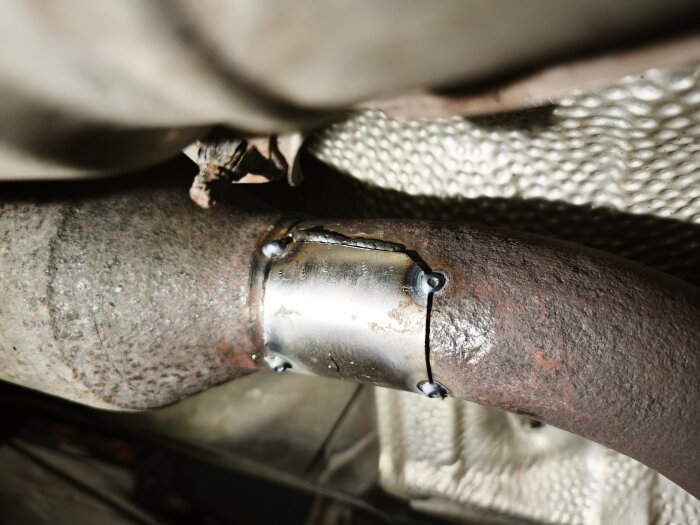 Svetsreparation på ett rostigt avgassystem med metallplåt och punktsvetsar. Dämpad gastryck saknas med 12 bar kvar i gasflaskan under påskhelgen.