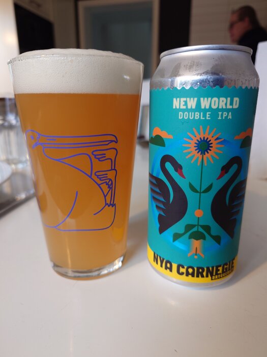 Ett glas öl bredvid en burk "New World Double IPA" från Nya Carnegie bryggeriet på ett bord.