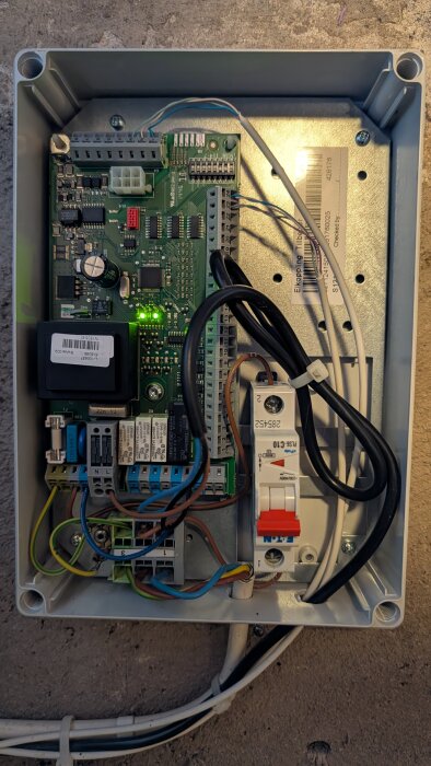 Närbild på kretskortet för en värmepump Nibe F1245 med tilslutna kablar och elektronik, sett uppifrån i en plastlåda.