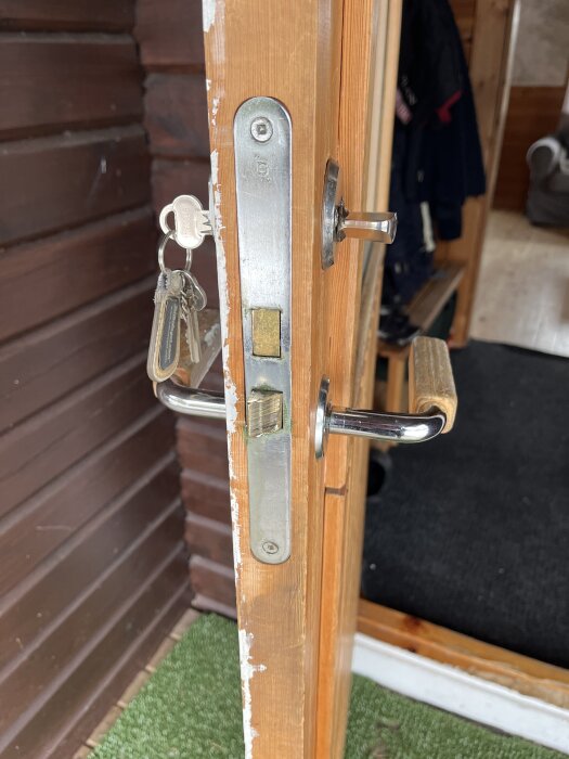 Dörr med nytt handtag och synliga nycklar, ej genomgående skruvstänger synliga på läskistan, frågan om äldre låskista som inte stöder nya skruvstänger.