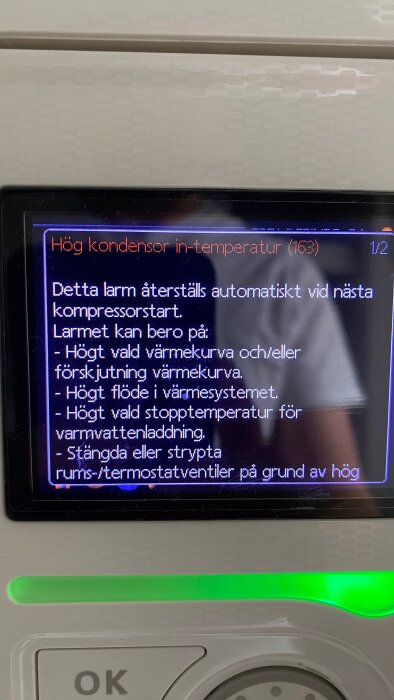 Värmepumpsdisplay visar larm om hög kondensor in-temperatur med möjliga orsaker som justering av värmekurva och flöde i värmesystemet.