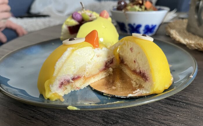 På bilden syns två gula bakelser med mousse och bärfyllning, dekorerade som påskkycklingar, på ett fat.