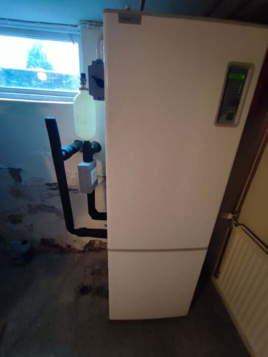 NIBE bergvärmepump i källare med synliga rörkopplingar och isolering.