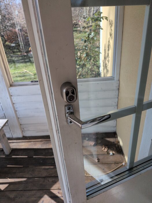 Nytt dörrhandtag på altandörr med smörjt lås, del av renoveringsprojekt.