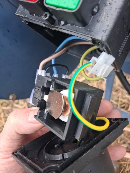 Innanmäte av strömbrytare till vedkap med exponerade kablar och komponenter, visar problem där brytaren inte stannar i på-läge.