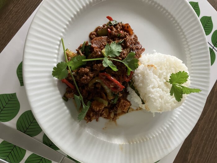 Tallrik med wokad köttfärssås och ris, toppad med koriander.