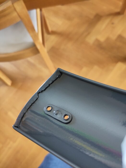 Närbild på en svart metalldel av en lådcykelram med applicerad underredsmassa, del av ett byggprojekt.