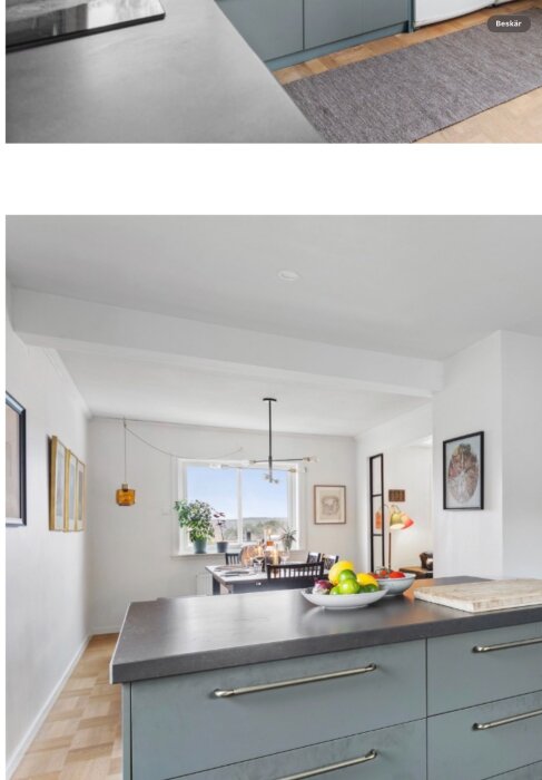 Modernt kök med öppen planlösning, ljus inredning, fruktskål på köksön, matbord vid fönster och förstärkt bärande balk i taket.