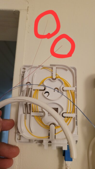 Bruten röd fiberkabel markerad med röda cirklar, visad nära anslutning. Kabeln behöver specialsvetsas för att återställas.