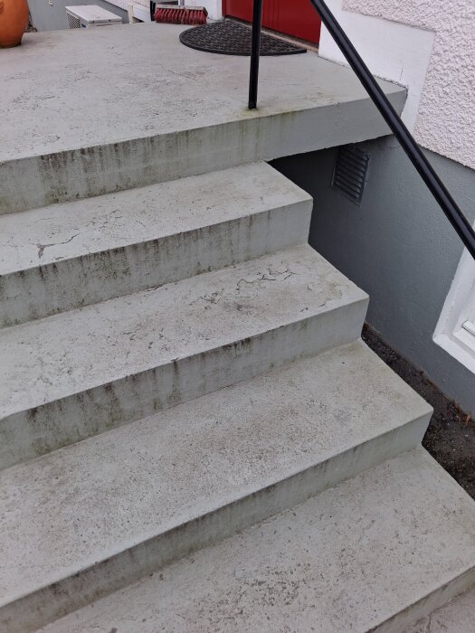 Sliten yttertrapp i betong målad med mineral putsfärg där färgen lossnar.