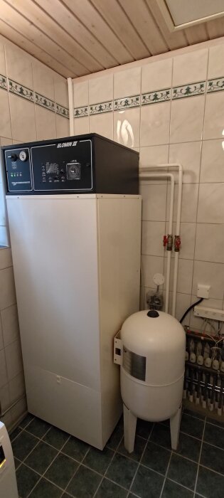 Elomin III elpanna i ett kaklat rum, med ett tryckkärl och rörsystem synligt.