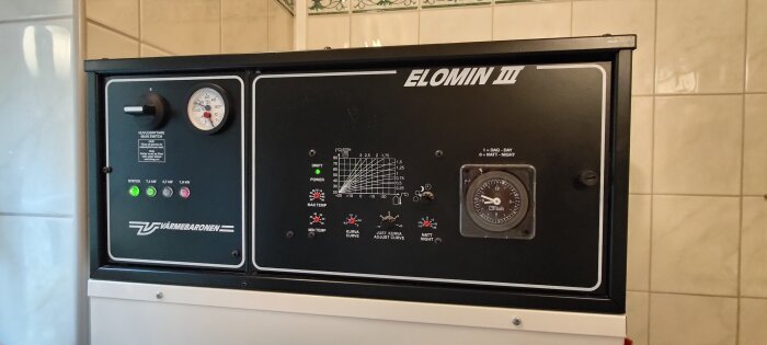 Elomin III elpanna från Värmebaronen med kontrollpanel inkl. manometer och termostatinställningar, installerad i ett badrum.