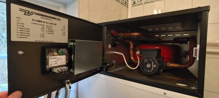 Insidan av en Elomin III elpanna med rördragning och elektriska komponenter synliga.