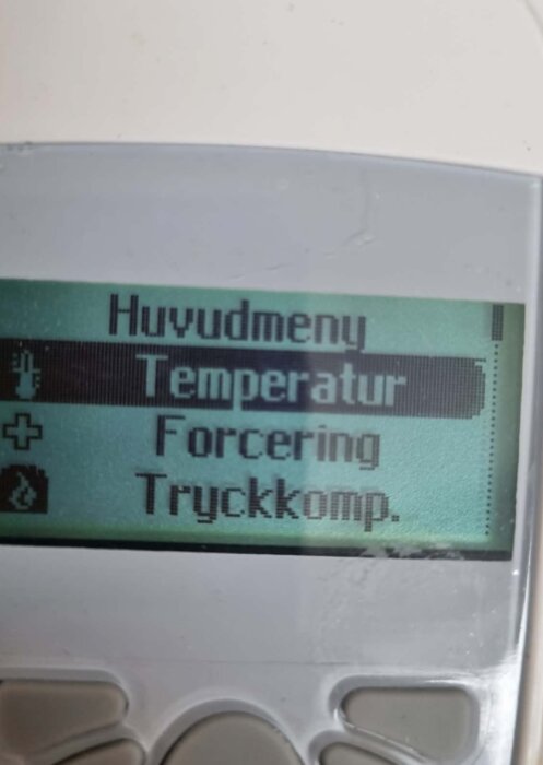 Fjärrkontrollens display visar huvudmenyn med alternativ för temperatur, forcering och tryckkompensering.