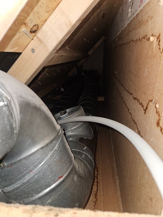 Ventilationsrör och kablar i ett trångt schakt bakom köksspisen, del av ett pågående projekt med Heru 100 aggregat och rördragning genom huset.