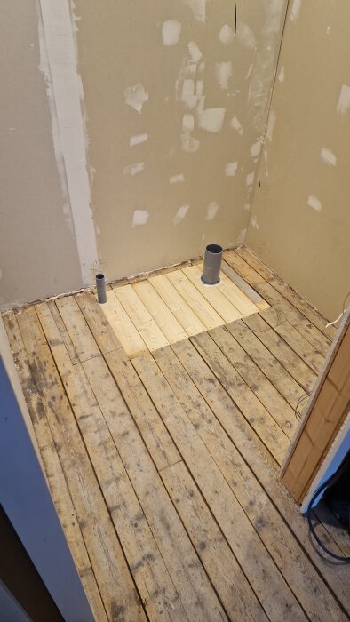 Renovering av gästtoalett med träundergolv och synliga avloppsrör i ett ofärdigt rum. Gipsväggarna runtom är delvis färdigställda.