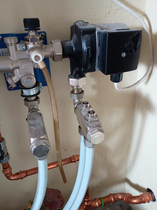 Vattenburen golvvärmeinstallation med rör, ventiler och pump i ett vardagsrum, uppvärmning kopplat till luft/vatten-värmepump.