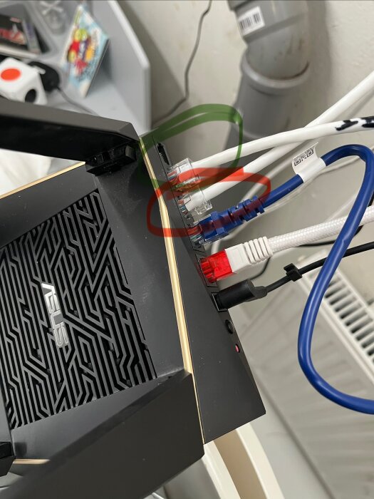 Router med nätverkskablar; en med grön markering fungerar korrekt, en med röd markering fungerar inte och går till ett annat uttag/rum.